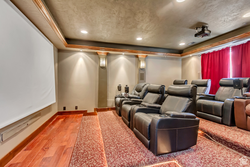 Home theater room featuring a raised ceiling, light wood-style flooring, baseboards, and recessed lighting