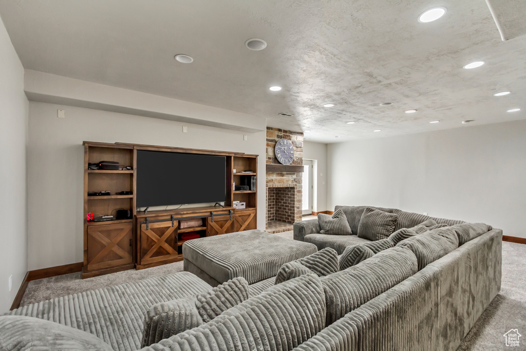 Carpeted living area featuring baseboards, recessed lighting, and a large fireplace