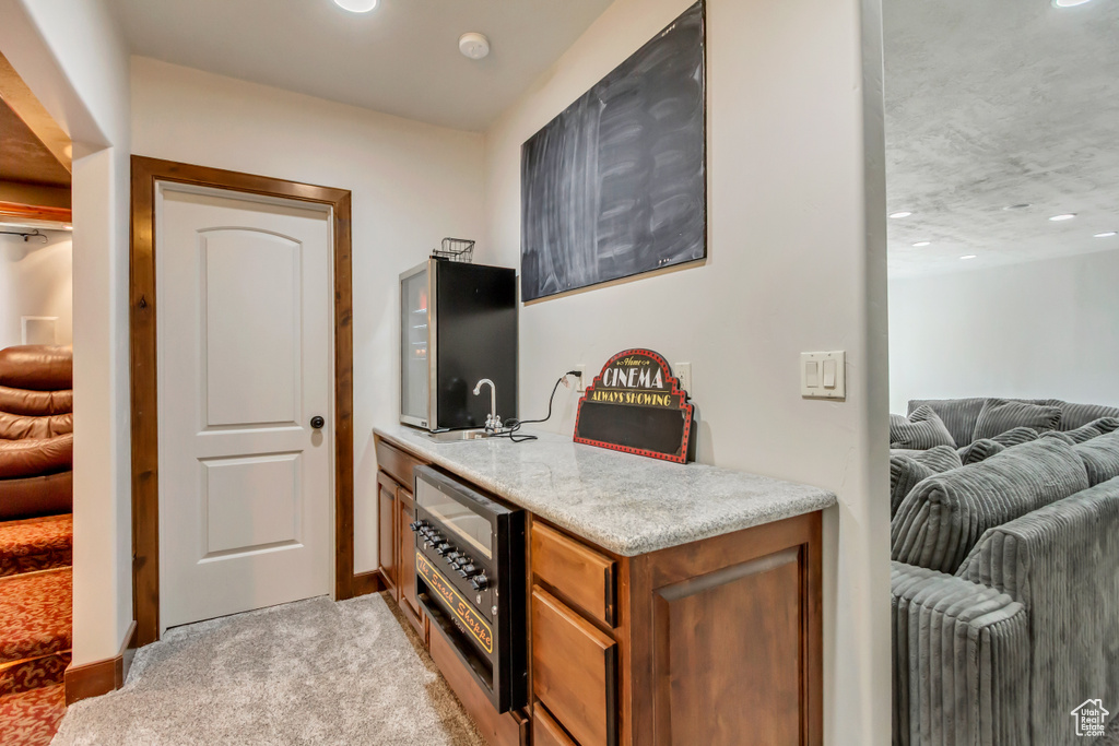 Indoor wet bar with light colored carpet, baseboards, and recessed lighting