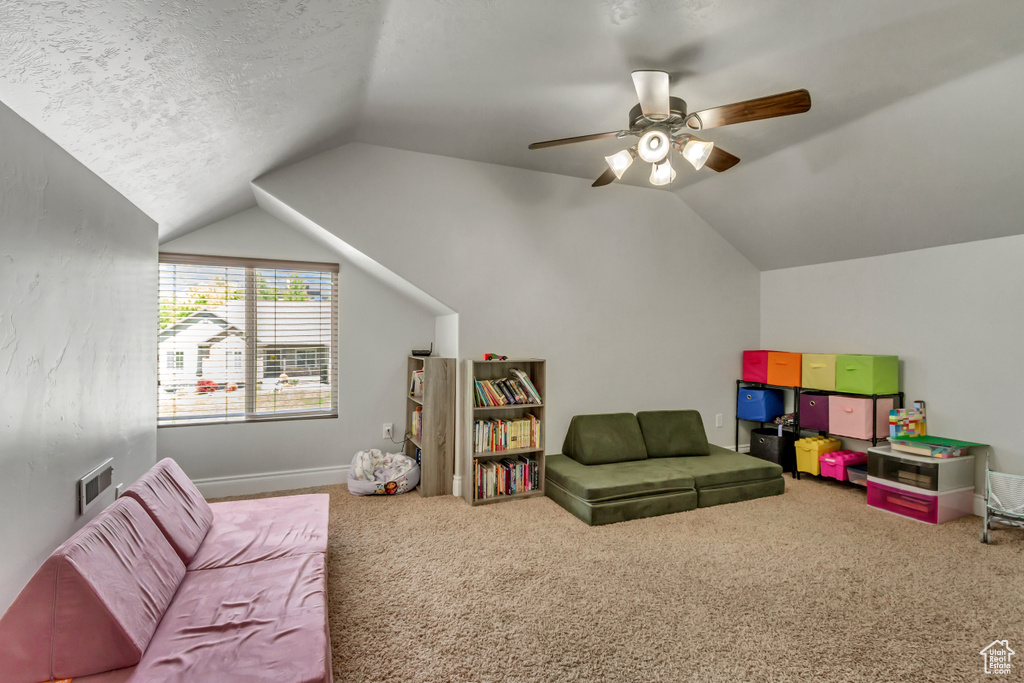 Game room with lofted ceiling, carpet flooring, ceiling fan, baseboards, and a textured ceiling