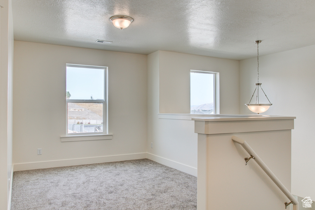 Unfurnished room featuring a textured ceiling, carpet floors, and baseboards
