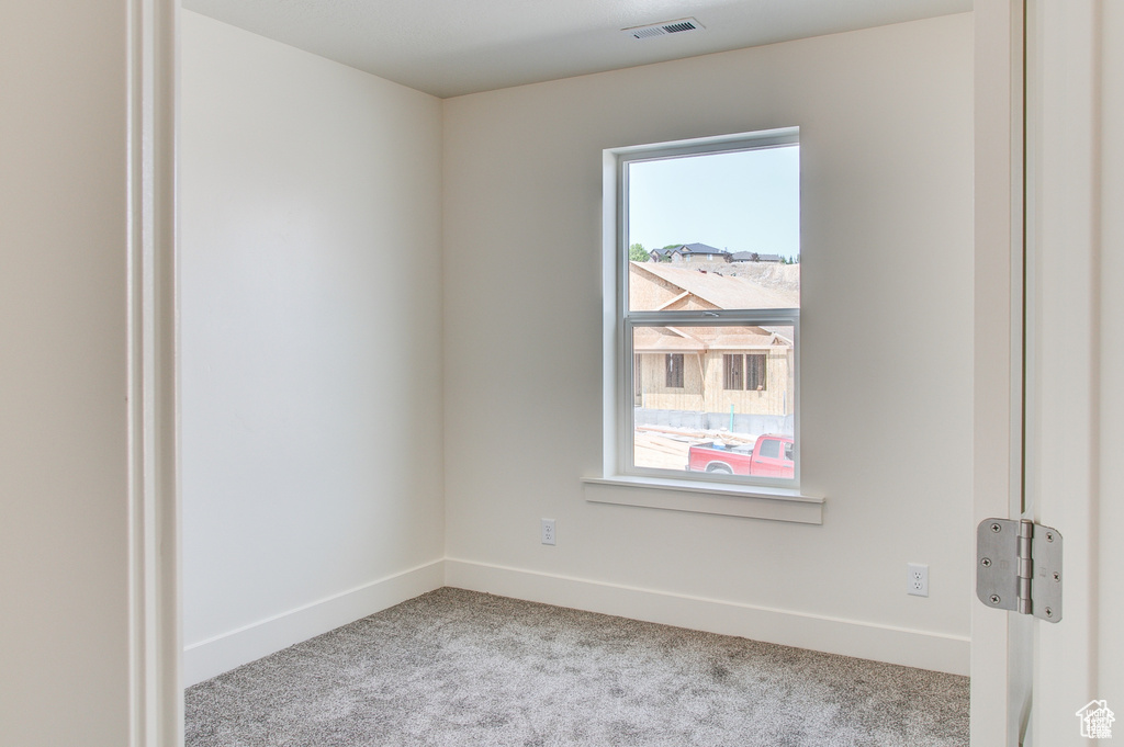 Spare room featuring carpet floors, plenty of natural light, and baseboards