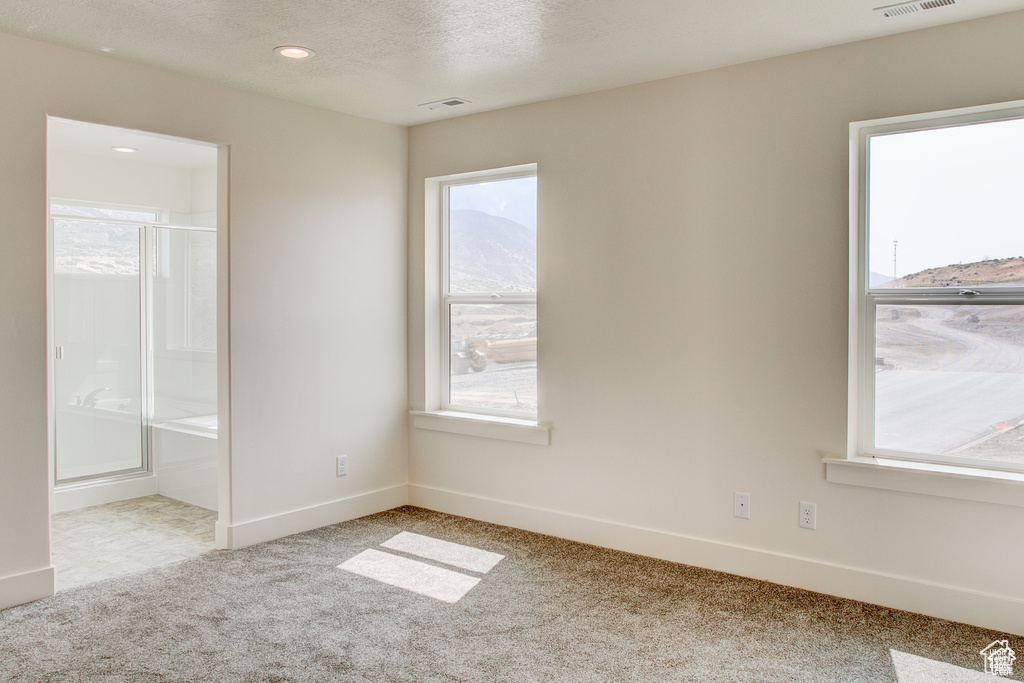 Unfurnished bedroom featuring carpet, multiple windows, baseboards, ensuite bath, and recessed lighting
