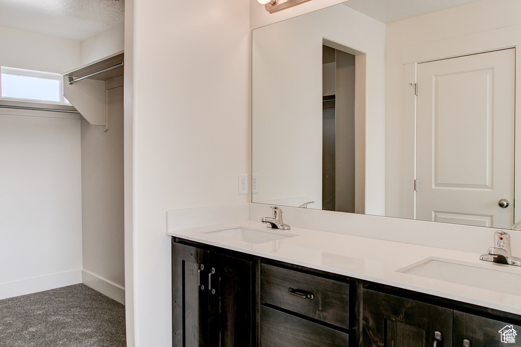 Full bath with baseboards, double vanity, and a closet