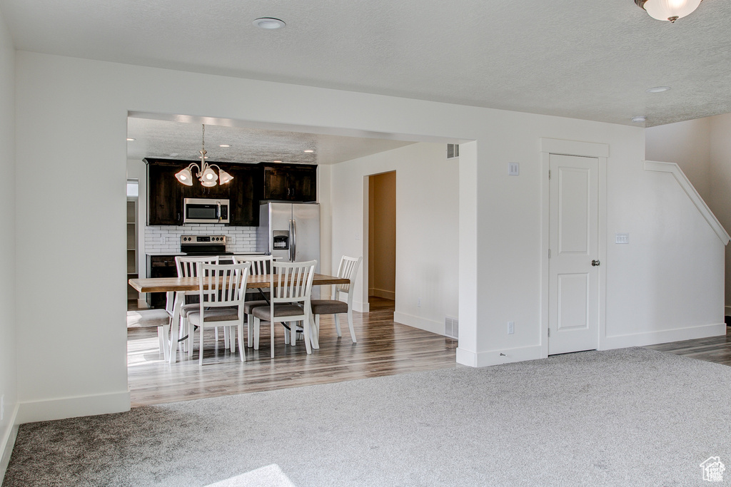 Dining space with light carpet, baseboards, a chandelier, and a textured ceiling