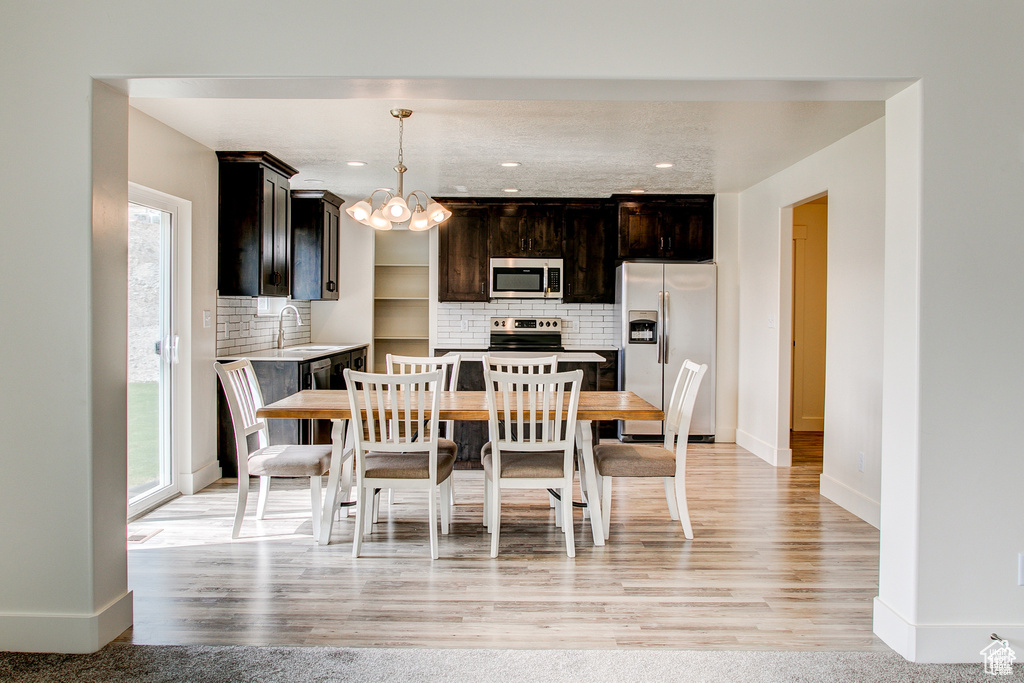 Dining space with plenty of natural light, a chandelier, baseboards, light wood-style floors, and recessed lighting