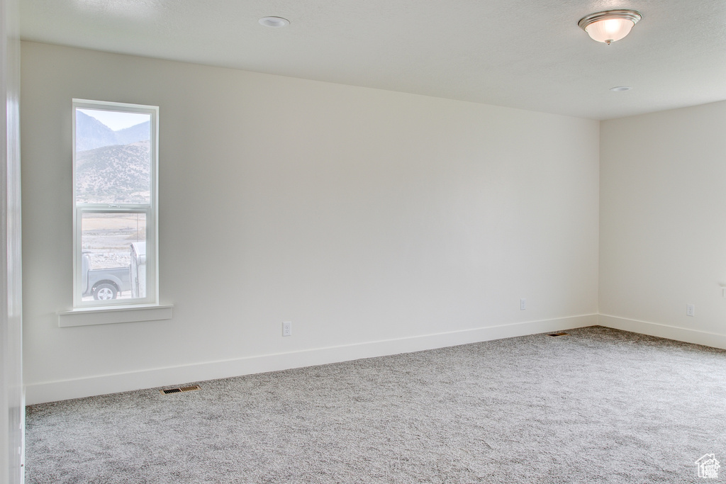 Carpeted spare room featuring baseboards