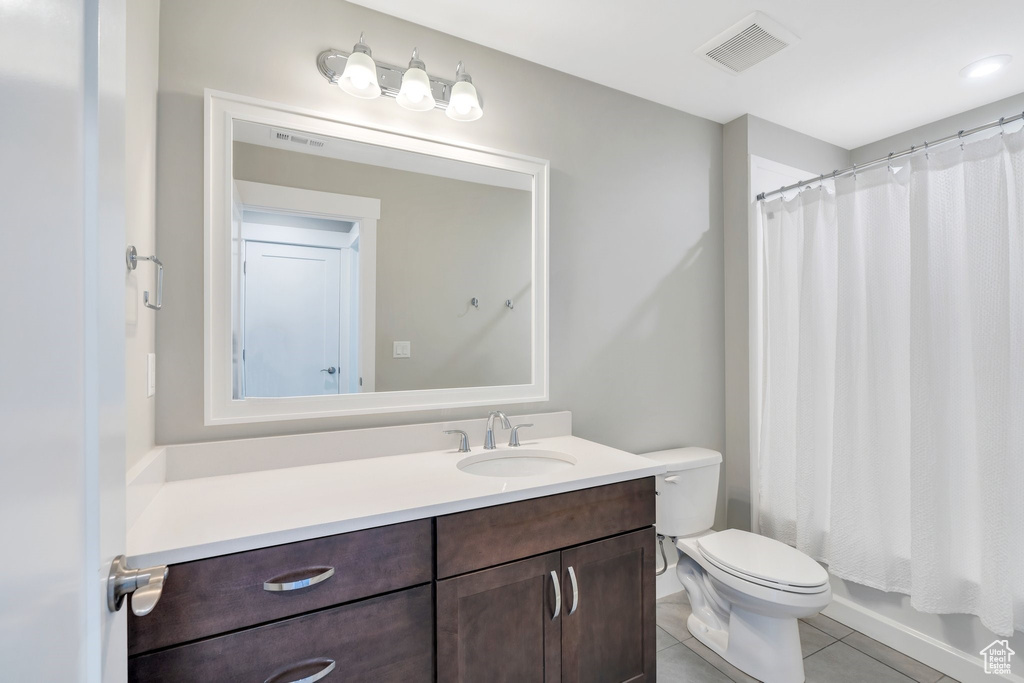 Bathroom with tile patterned flooring, vanity, curtained shower, and toilet
