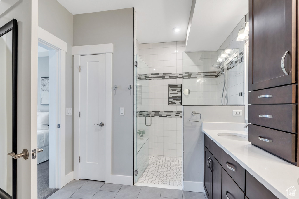 Bathroom with tile patterned flooring, tiled shower, vanity, baseboards, and ensuite bath