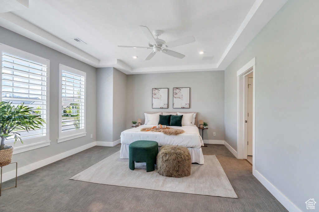 Bedroom featuring carpet floors, recessed lighting, baseboards, ceiling fan, and a tray ceiling