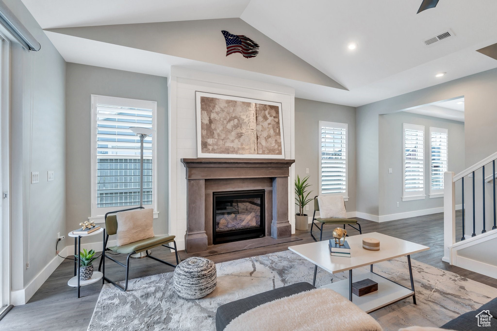 Living room with lofted ceiling, wood finished floors, a fireplace, baseboards, and recessed lighting