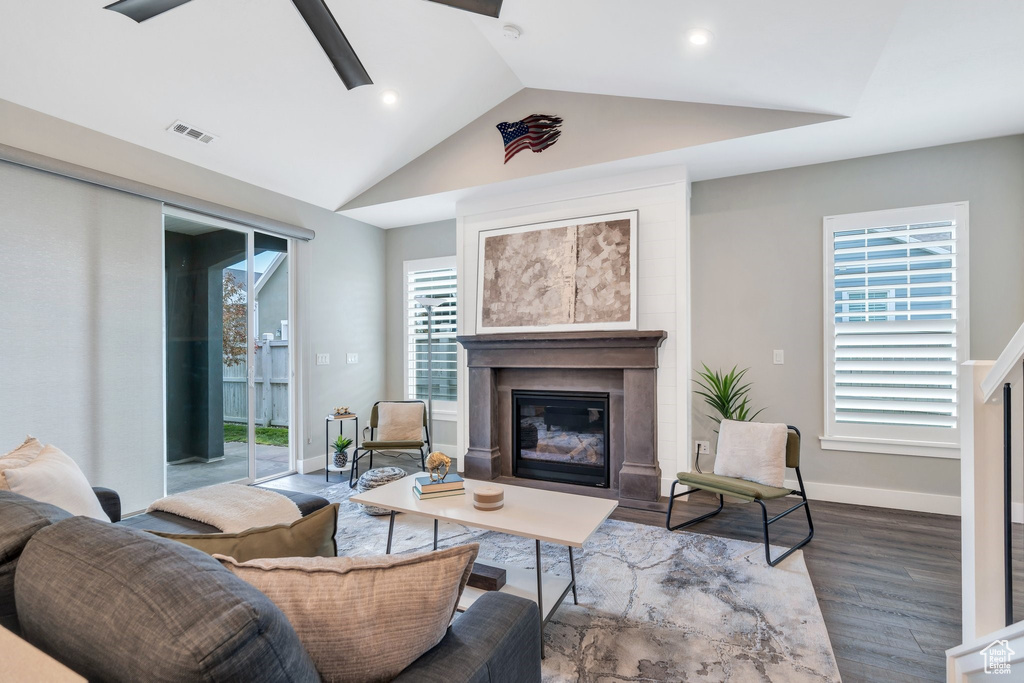 Living room with a glass covered fireplace, wood finished floors, lofted ceiling, a ceiling fan, and baseboards
