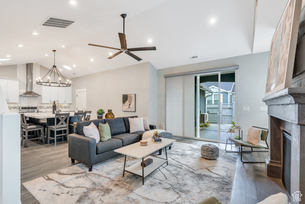 Living area with light wood-style flooring, a fireplace, high vaulted ceiling, a chandelier, and recessed lighting