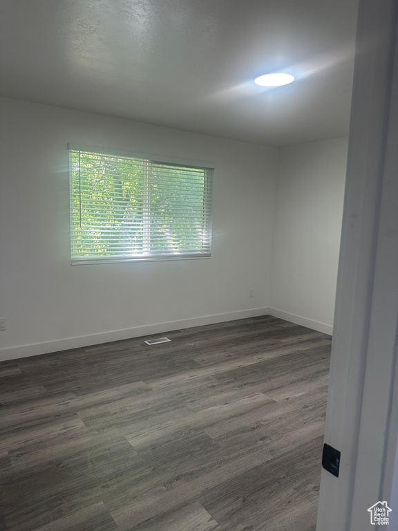 Empty room featuring dark wood-type flooring and baseboards