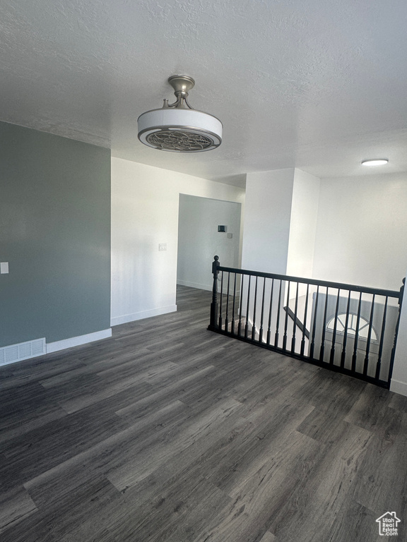 Spare room featuring baseboards, wood finished floors, and a textured ceiling