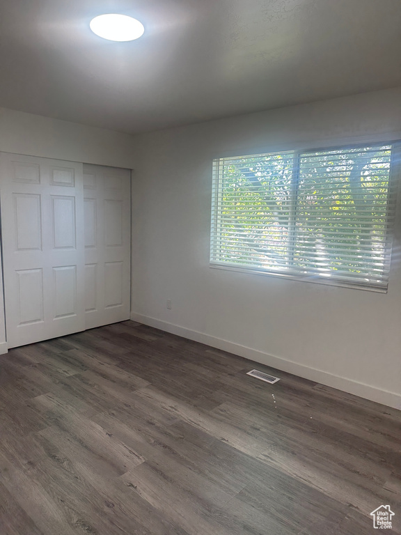 Unfurnished bedroom with baseboards, dark wood-type flooring, and a closet
