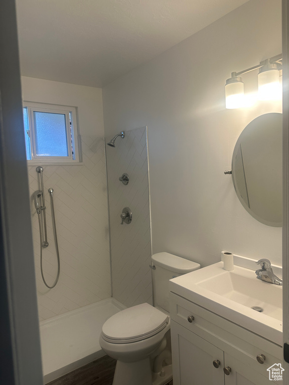 Full bathroom with toilet, a tile shower, and vanity