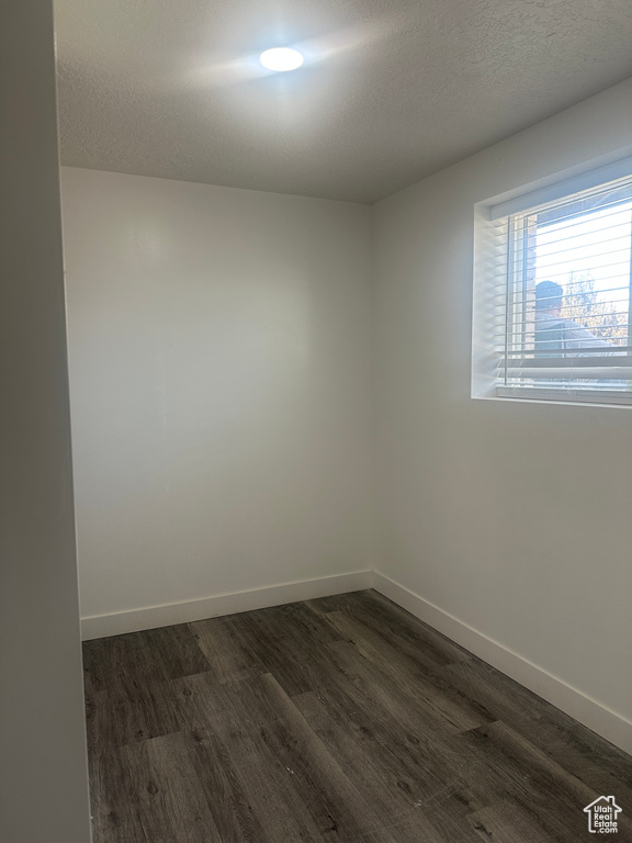 Spare room with dark wood-type flooring, baseboards, and a textured ceiling