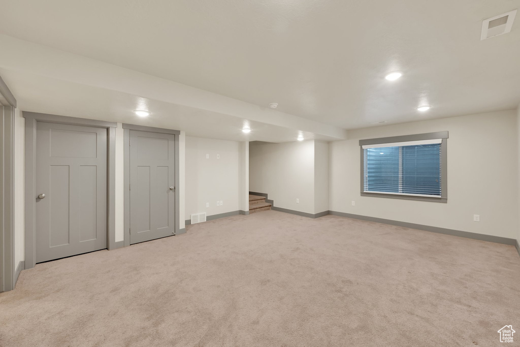 Finished below grade area with baseboards, light colored carpet, stairs, and recessed lighting