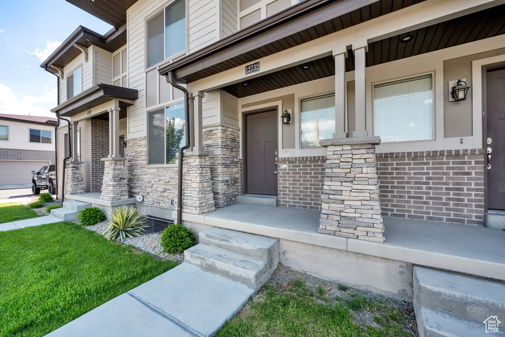 Doorway to property with covered porch and stone siding