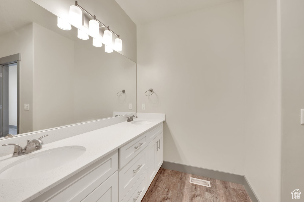 Full bath featuring wood finished floors, double vanity, and baseboards