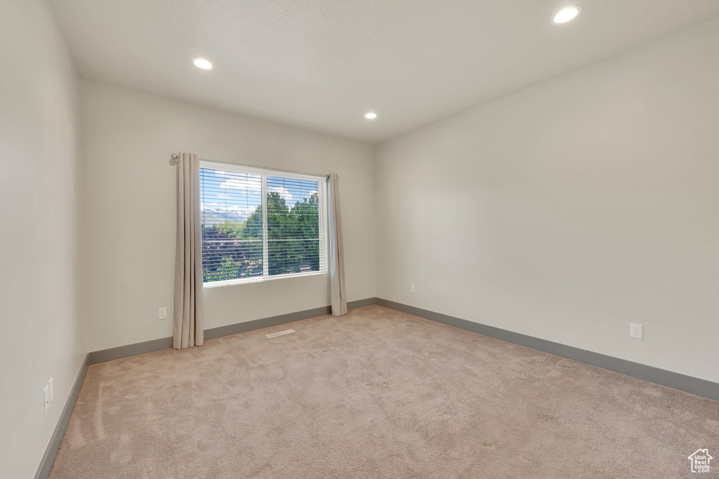 Spare room featuring light carpet, recessed lighting, and baseboards