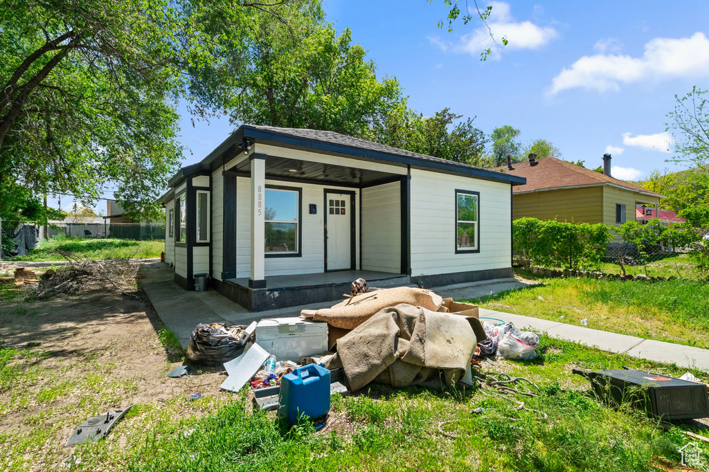 View of outdoor structure featuring a porch and fence