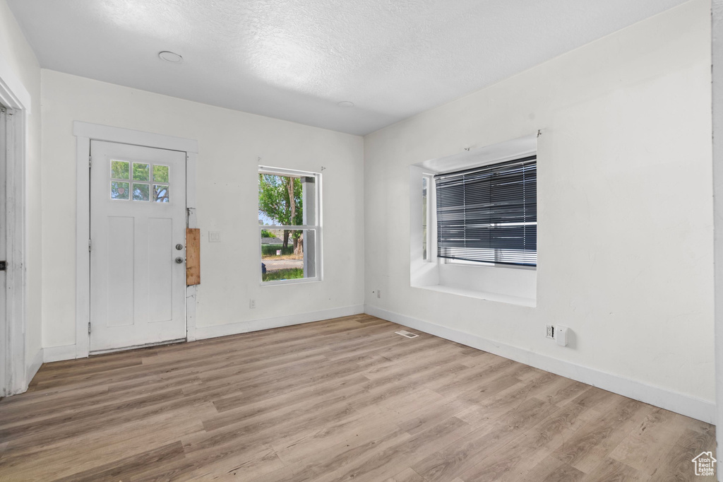 Foyer featuring light wood-type flooring, baseboards, and a textured ceiling
