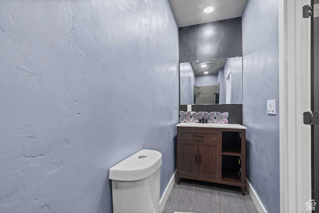 Bathroom featuring toilet, baseboards, vanity, and tile patterned floors