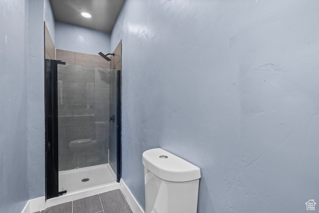 Full bath with toilet, baseboards, and a shower stall
