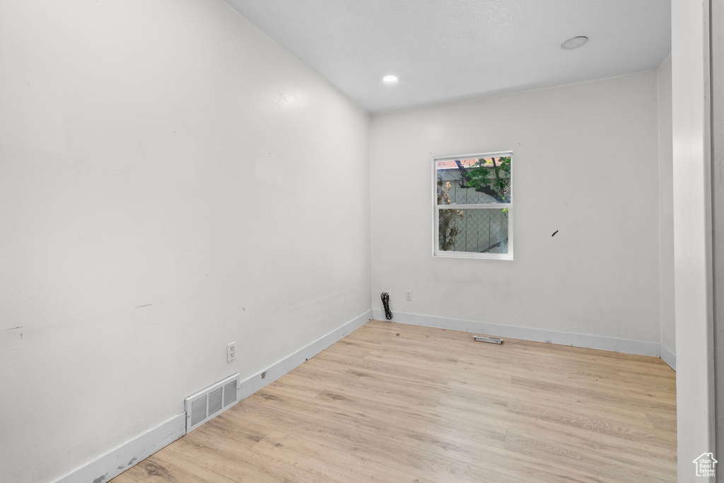 Empty room featuring wood finished floors, baseboards, and recessed lighting