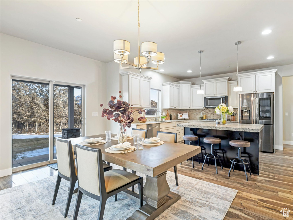 Dining area featuring a chandelier, light wood-type flooring, baseboards, and recessed lighting