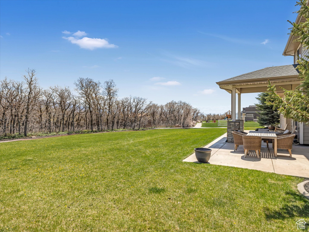 View of grassy yard featuring a patio area