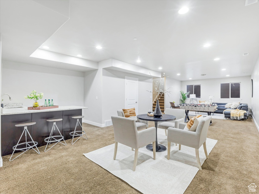 Dining area featuring light colored carpet, bar with sink, recessed lighting, and baseboards