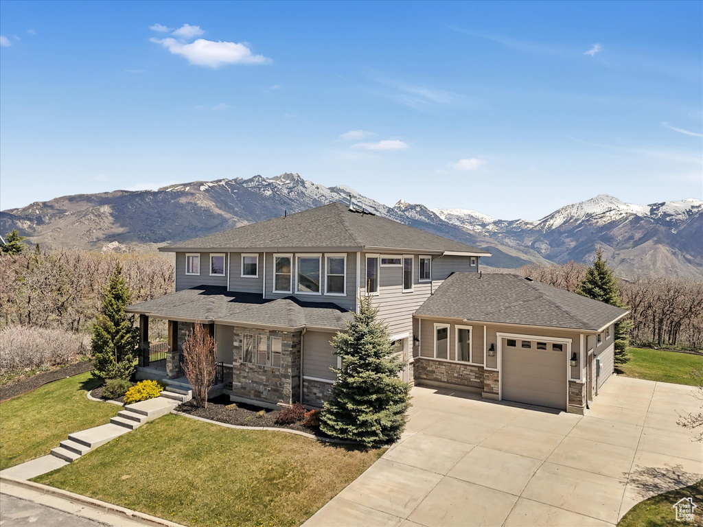 Prairie-style home with covered porch, an attached garage, a mountain view, and driveway