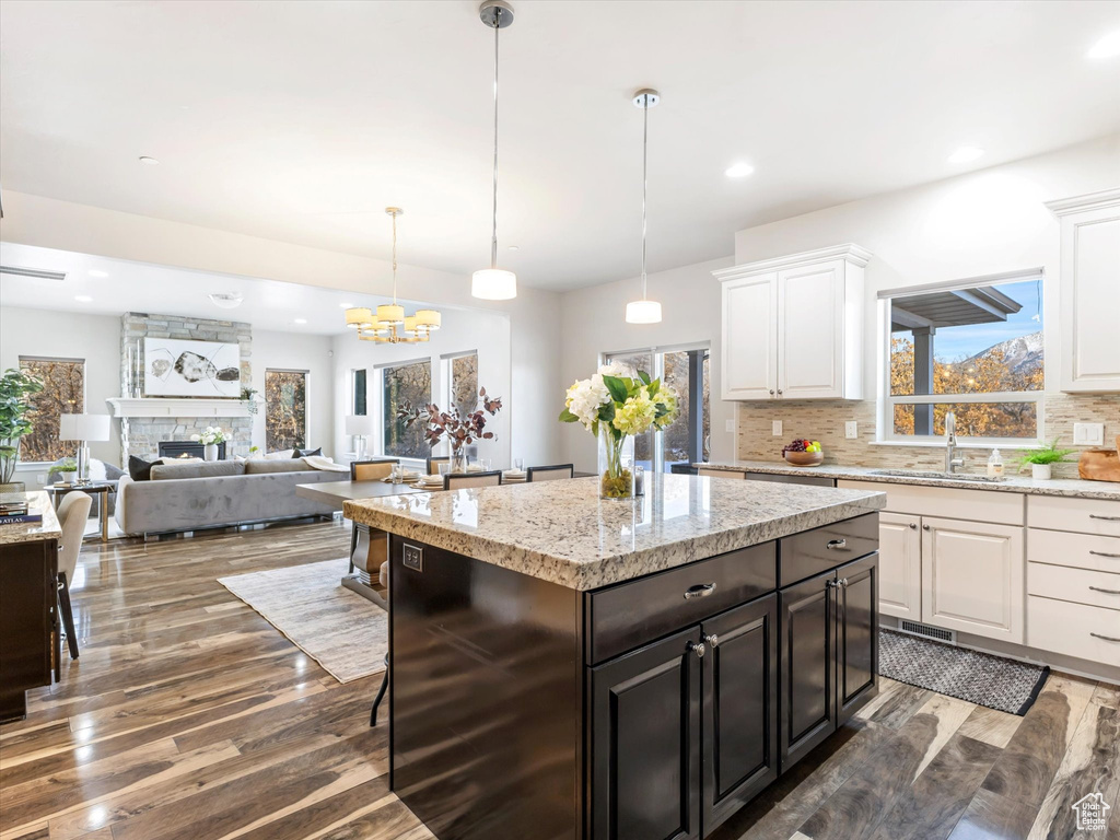 Kitchen with wood finished floors, white cabinetry, tasteful backsplash, a sink, and a center island