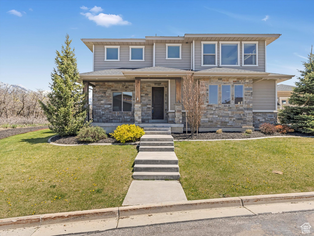 View of front of property featuring stone siding, a porch, and a front yard