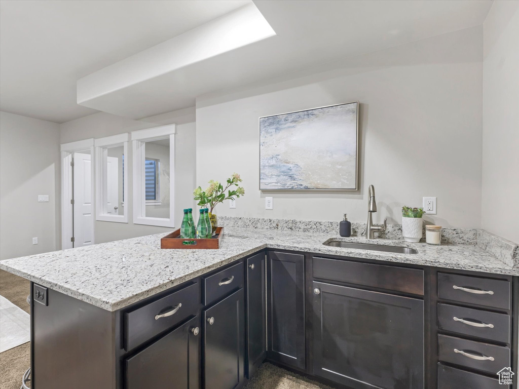 Kitchen with a sink, a peninsula, and light stone countertops