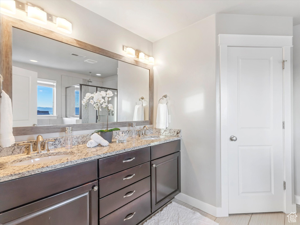 Bathroom featuring a stall shower, baseboards, and double vanity