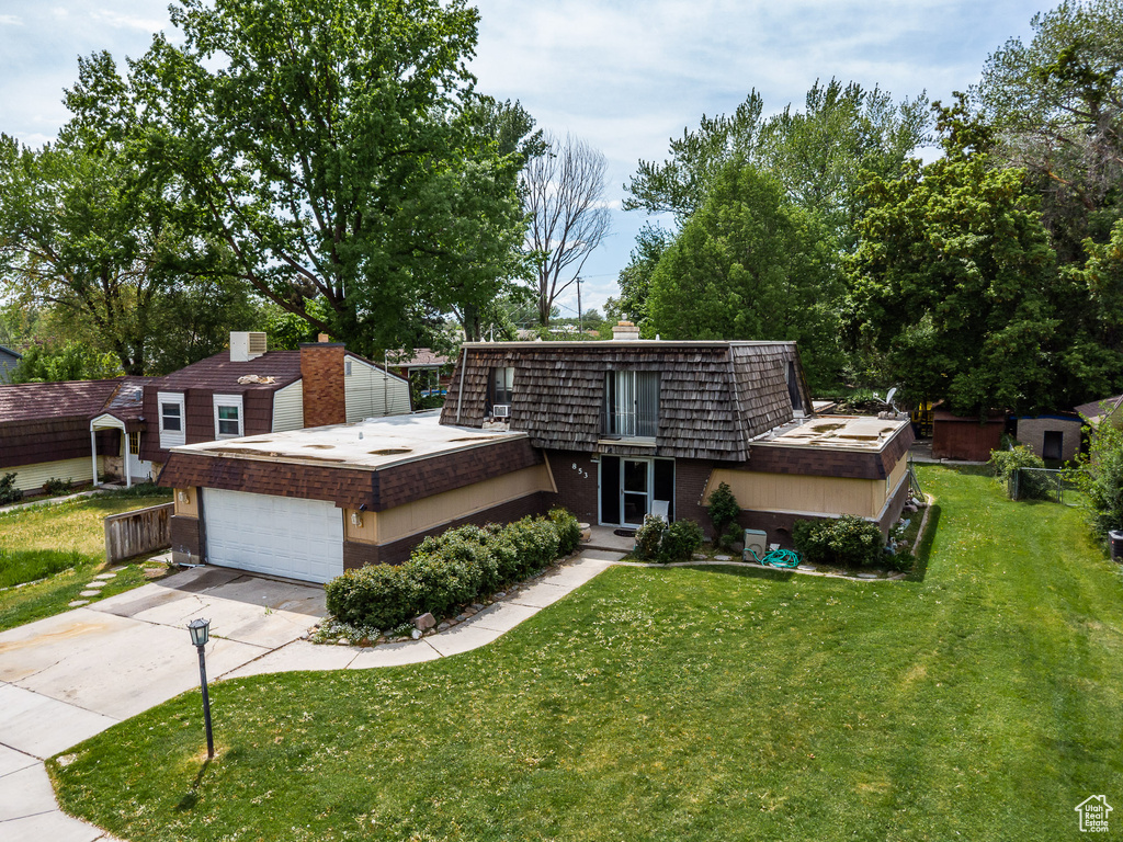 Front of property with mansard roof, a front lawn, concrete driveway, and a chimney