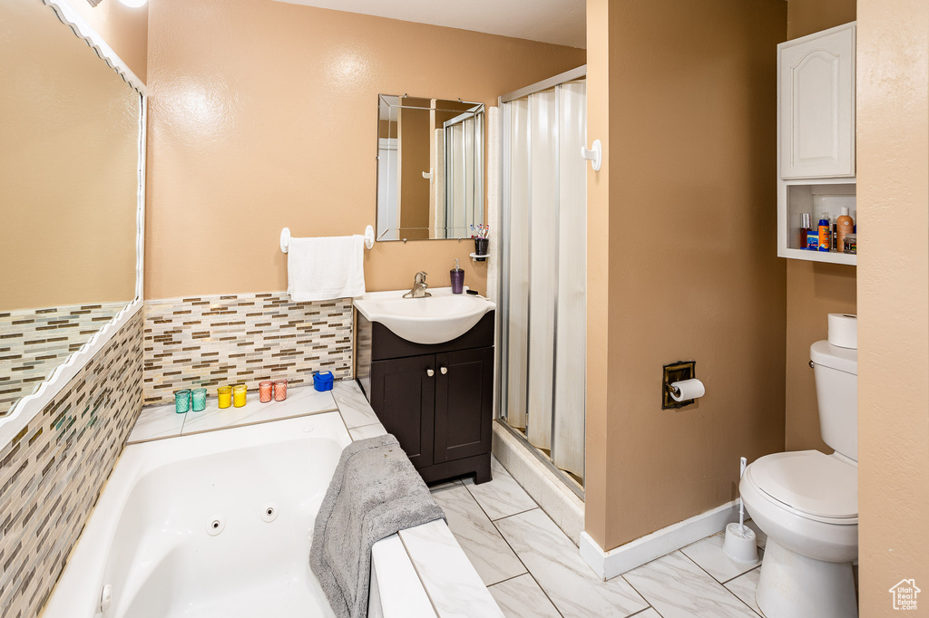 Bathroom featuring toilet, vanity, a tub with jets, a stall shower, and marble finish flooring