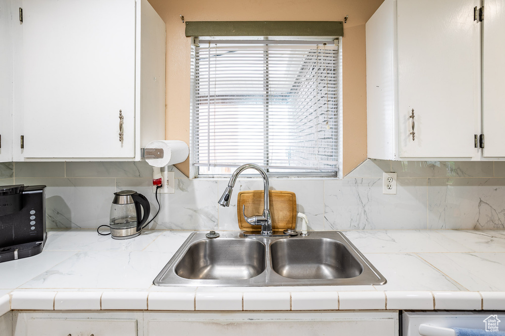 Kitchen featuring a sink, white cabinets, and light countertops