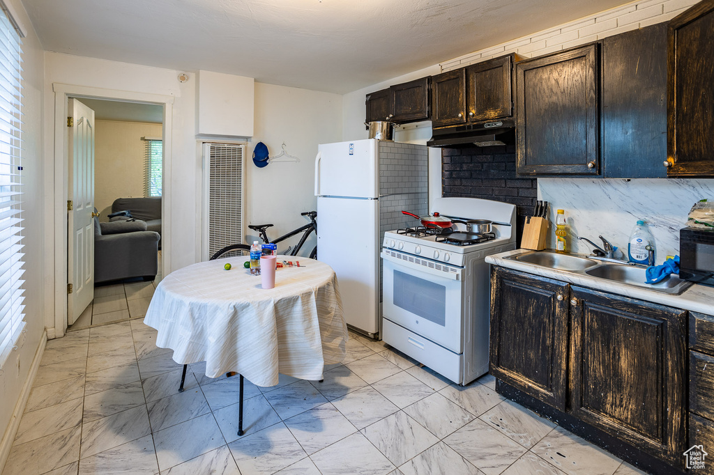 Kitchen with white appliances, light marble finish flooring, a sink, under cabinet range hood, and a heating unit