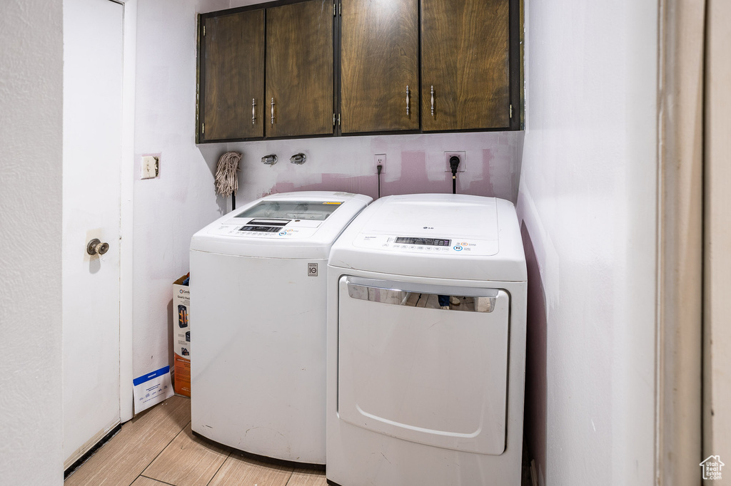 Laundry room with cabinet space, separate washer and dryer, and light wood finished floors