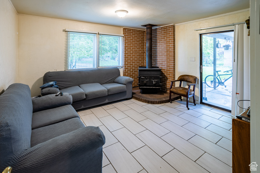 Living room with a wood stove, crown molding, and plenty of natural light