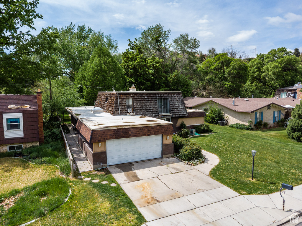 View of front of home featuring a front lawn, a garage, a chimney, and concrete driveway