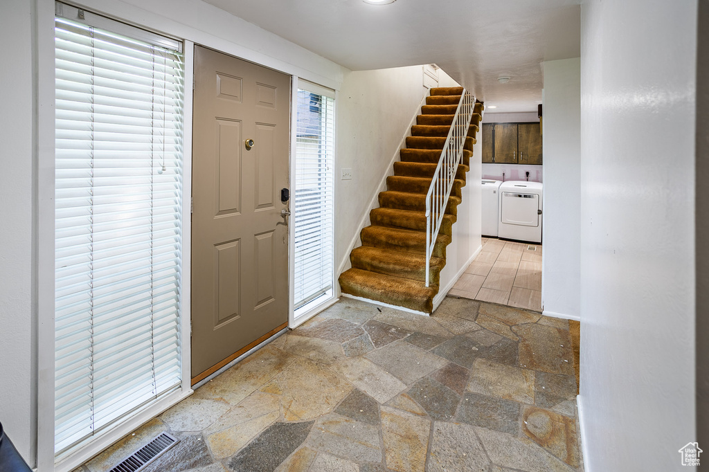 Foyer featuring washing machine and dryer, stone tile flooring, and stairs