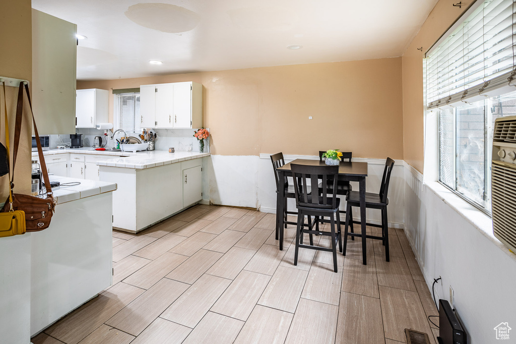 Kitchen with healthy amount of natural light, tile countertops, white cabinets, and wood finish floors