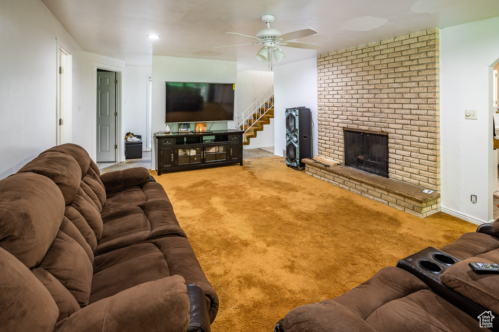 Living area featuring a ceiling fan, a fireplace, carpet floors, stairs, and baseboards