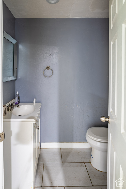 Bathroom featuring toilet, tile patterned flooring, vanity, and baseboards